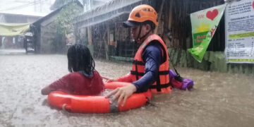 This handout photo taken and received on December 16, 2021 from the Philippine Coast Guard (PCG) shows a Coast Guard member (R) assisting a flood-affected resident in a flotation ring during an evacuation from their homes next to a swollen river in Cagayan de Oro city on southern Mindanao island, amid heavy rains brought about by Super Typhoon Rai. (Photo by Handout / AFP) / -----EDITORS NOTE --- RESTRICTED TO EDITORIAL USE - MANDATORY CREDIT "AFP PHOTO / PHILIPPINE COAST GUARD (PCG) " - NO MARKETING - NO ADVERTISING CAMPAIGNS - DISTRIBUTED AS A SERVICE TO CLIENTS