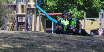 This photo taken and provided on December 17, 2021 by The Advocate/ACM shows members of the local police reacting near a playground outside the Hillcrest Primary School the day after five children died and four others were injured when a bouncy castle was blown into the air at an end-of-term school party in the Tasmania city of Devonport. (Photo by Simon Sturzaker / various sources / AFP) / - Australia OUT / --- RESTRICTED TO EDITORIAL USE ---- MANDATORY CREDIT: The Advocate/ACM