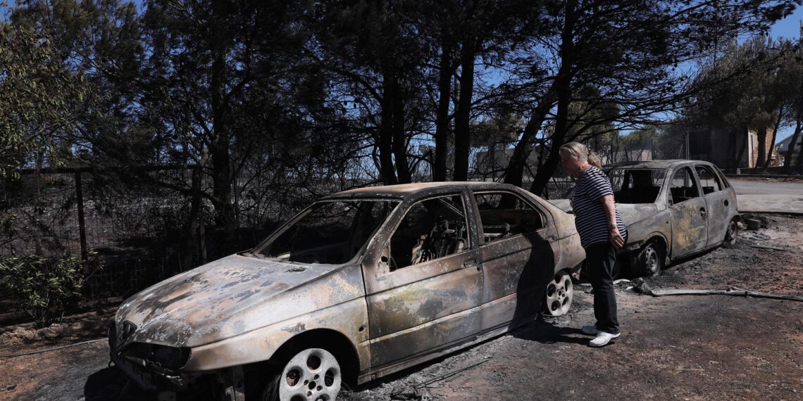 Una mujer observa los coches quemados del incendio acaecido en Anthousa, cerca de Atenas, Grecia. EFE/EPA/GEORGE VITSARAS