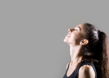 Stylish sporty young woman lifestyle portrait. Profile of fit girl breathing deep fresh air. Happy caucasian female dreaming with closed eyes and smiling. Studio image. Dark background