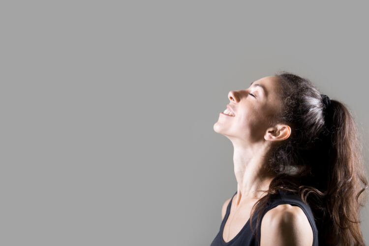 Stylish sporty young woman lifestyle portrait. Profile of fit girl breathing deep fresh air. Happy caucasian female dreaming with closed eyes and smiling. Studio image. Dark background
