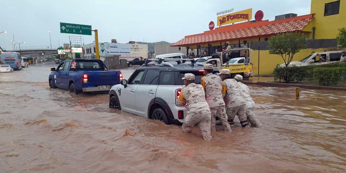 Soldados del Ejército Mexicano auxilian hoy a un conductor atrapado en una inundación producida por fuertes lluvias en la ciudad de Nogales, estado de Sonora (México). EFE/Daniel Sánchez