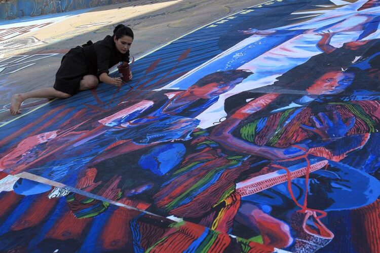 La artista y activista de la fundación internacional “Haznos valer”, Karina Brezee, pinta un mural bajo el puente internacional Paso del Norte hoy, en Ciudad Juárez, Chihuahua (México). EFE/Luis Torres