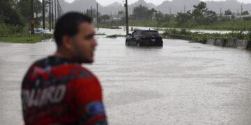 Un hombre observa un automóvil en una calle inundada debido a lluvias ocasionadas por el paso del huracán Fiona, el 19 de septiembre de 2020, en Toa Baja (Puerto Rico). EFE/Thais Lorca