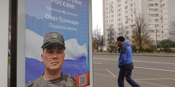 Un hombre camina por una calle de Moscú junto a un cartel que recuerda a los soldados que participan en la guerra en Ucrania. EFE/EPA/MAXIM SHIPENKOV