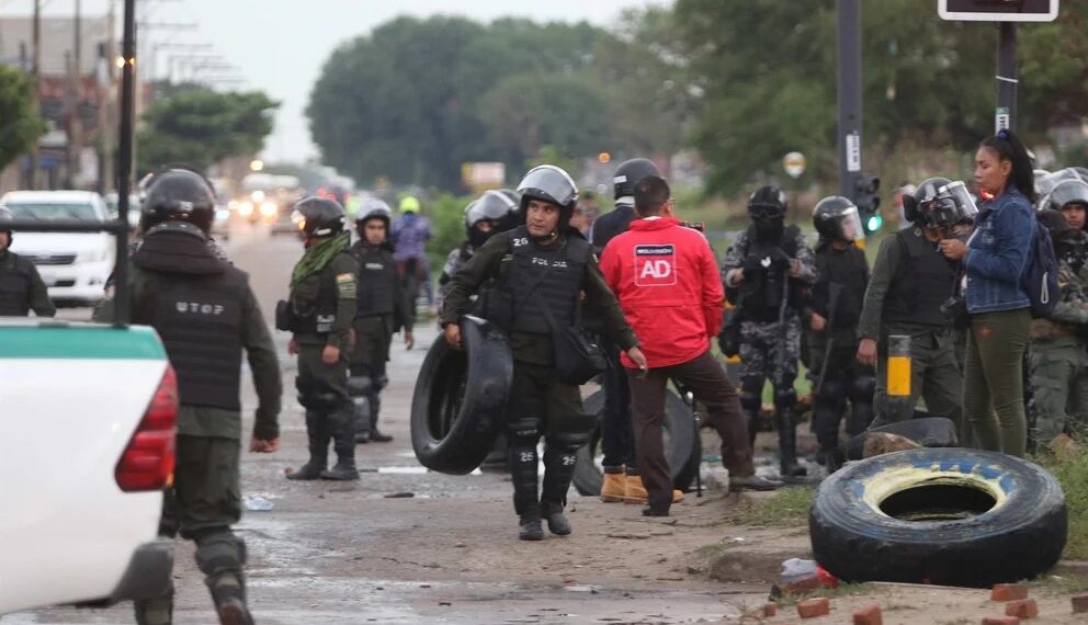 Policías antimotines de Bolivia retiran unos neumáticos que eran usados para bloquear calles en Santa Cruz (Créditos: EFE)