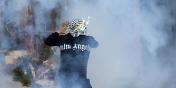 Un manifestante palestino arroja un bote de gas lacrimógeno durante los enfrentamientos tras una manifestación contra los asentamientos israelíes cerca de la ciudad cisjordana de Nablús (Foto: EFE)