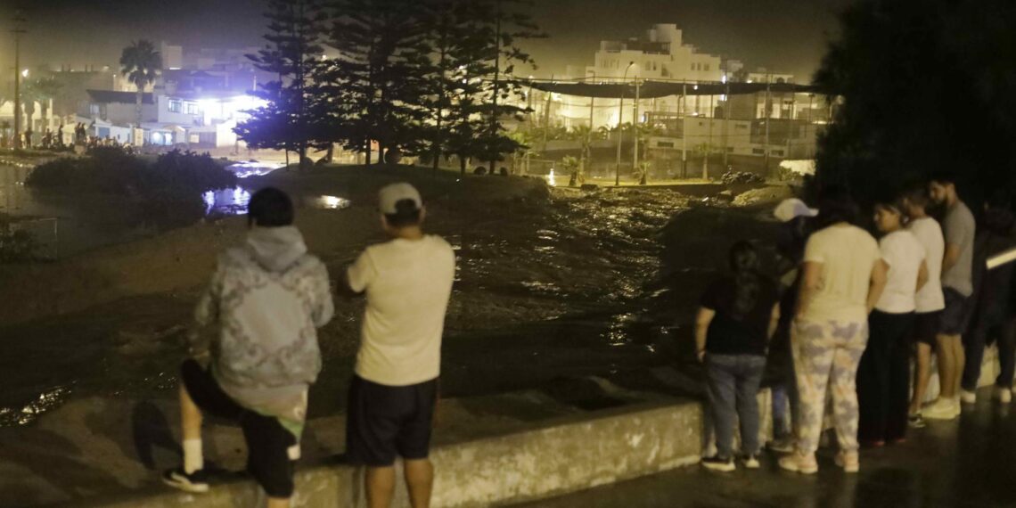 Pobladores de Punta Hermosa fueron registrados esta madrugada al observar los estragos del aluvión de lodo que inundó sus calles, en el sur de Lima (Perú). EFE/Stringer