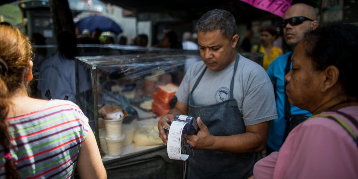 Fotografía de archivo en la que se registró a un tendero con un datáfono en un mercado callejero de alimentos, en Caracas (Venezuela). EFE/Miguel Gutiérrez