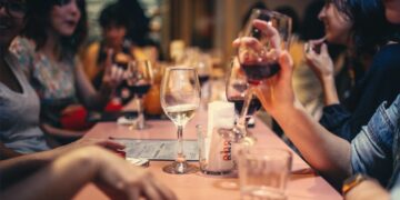 Gente bebiendo vino en una mesa. Imagen referencial: Pexels/Helena Lopes.