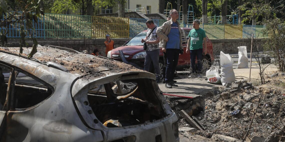 Varias personas observan un agujero causado por un proyectil y un automóvil dañado tras un ataque con drones en Kiev, Ucrania, el 30 de mayo de 2023. EFE/EPA/SERGEY DOLZHENKO