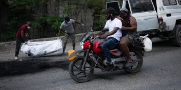 Dos hombres cargan el cuerpo incinerado de una persona hoy, en Puerto Príncipe (Haití). EFE/ Johnson Sabin