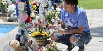 Cynthia Flores coloca flores y arregla el memorial de José Flores Jr. de su hijo durante una vigilia en la Plaza Uvalde, realizada para conmemorar el primer aniversario del tiroteo masivo en la Escuela Primaria Robb. EFE/EPA/ADAM DAVIS