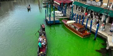 Una góndola cruza el histórico Gran Canal de Venecia mientras una mancha de líquido verde fluorescente se extiende en él, el domingo 28 de mayo de 2023. (Foto: Luigii Costantini/AP)