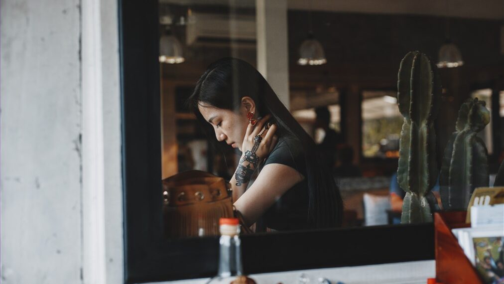 Un mujer tatuada tomándose del cuello. Foto: Pexels/@roman-odintsov