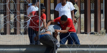 Migrantes cruzan las alambradas con filosas cuchilas colocadas en los muros hoy para entregarse a las autoridades y pedir asilo en Ciudad Juárez, Chihuahua (México). EFE/Luis Torres