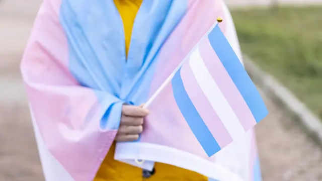 Mujer transgénero cubierta con la bandera transgéneroGETTY IMAGES