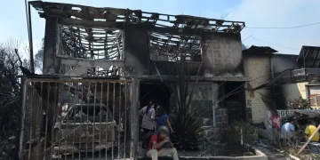 Personas permanecen afuera de una casa quemada tras un incendio que afectó a los cerros en la comuna de Quilpué, Viña del Mar, Chile, el 3 de febrero de 2024. (Crédito: RODRIGO ARANGUA/AFP/Getty Images)