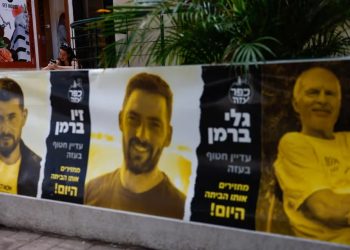 Una mujer utiliza su teléfono celular en Tel Aviv, cerca de los afiches con imágenes de los secuestrados por el grupo terrorista Hamas el 7 de octubre de 2023 (REUTERS/Carlos Garcia Rawlins)