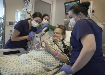 Lisa Pisano mira fotos de su perro después de ser operada en el hospital NYU Langone Health en Nueva York, 22 de abril de 2024. (AP Photo/Shelby Lum)
