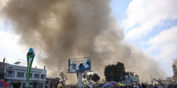 Palestinians look at smoke billowing during Israeli bombardment on the Firas market area in Gaza City on April 11, 2024, amid the ongoing conflict between Israel and the Palestinian Hamas group. (Photo by AFP)