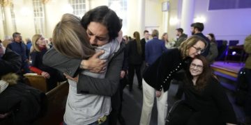 Tim Hernandez abraza a Kallie Leyba mientras la exlegisladora de Arizona Gabby Giffords (segunda por la derecha) abraza a Anne Marie Hochhalter, durante una vigilia con motivo del 25to aniversario de un letal tiroteo masivo en la Escuela Secundaria Columbine, el 19 de abril de 2024, en Denver. (AP Foto/Jack Dempsey)